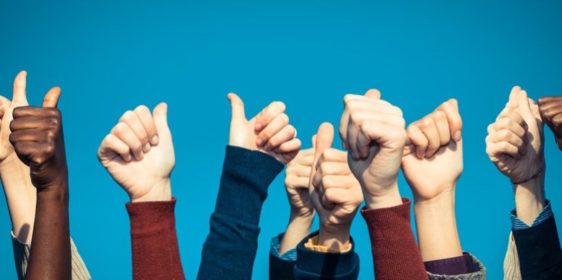 Multiracial Thumbs Up Against Blue Sky
