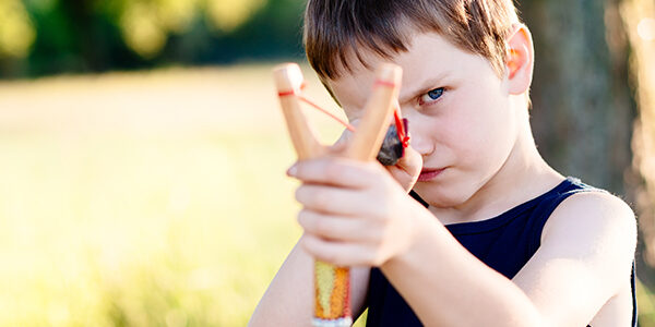 Little boy playing with slingshot
